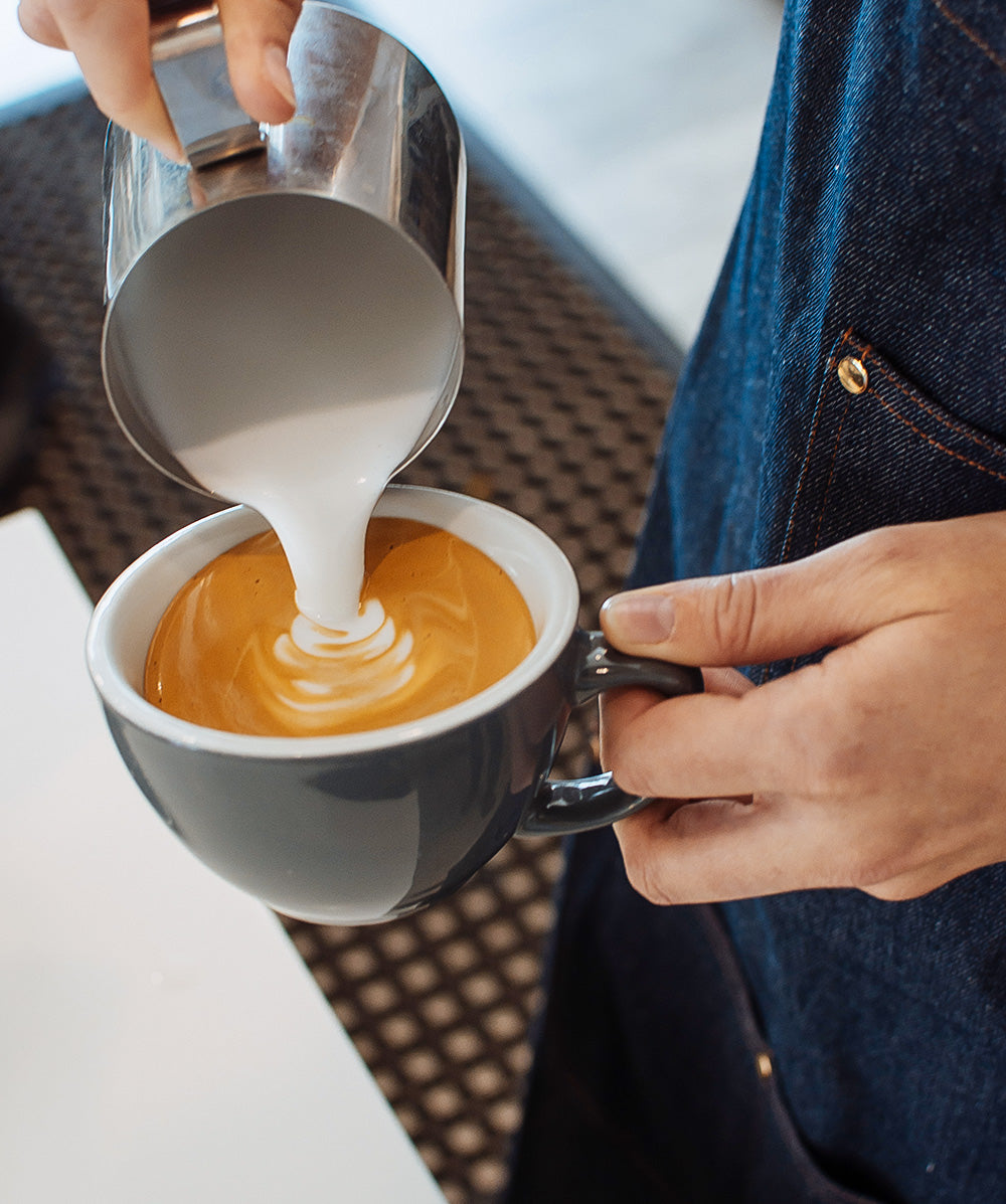 Barista showing proper pouring technique for a latte.