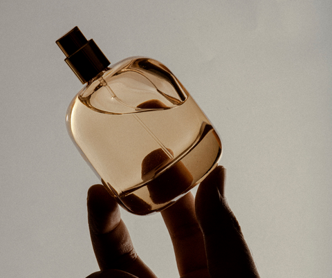 close up picture of clean perfume bottle being held by fingers