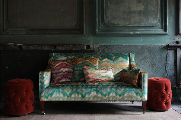 velvet upholstered sofa with patterned Susi Bellamy cushions on it