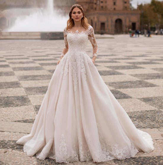 Elegant princess with long hair in wedding attire facing away from camera  with tiara and veil in diamond-studded lace ball gown with hands on a  balcony looking towards the moon and a