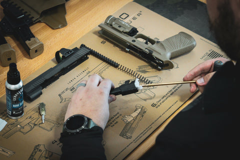 Pushing a rod through the barrel of the handgun to ensure the barrel is free of carbon build up