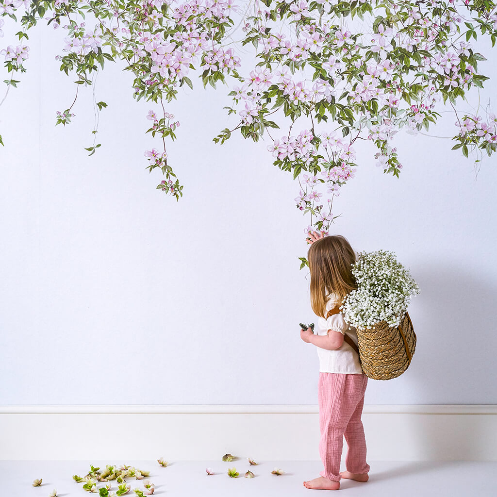 Niña admirando mural de pared floral rosa para habitaciones para niños