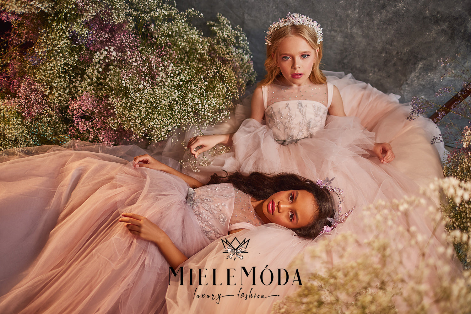flower girls wearing high end couture pink dresses by miele moda luxury fashion sitting surrounded by flowers