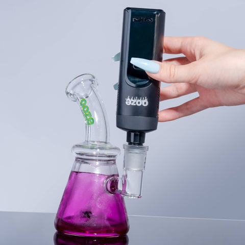 A black Verge is flipped upside down and attached to a purple Glyco bong using the water pipe adapter.