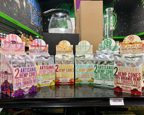 Counter displays of High Hemp tobacco-free cone 2-packs are lined up in an arc on a black shelf.