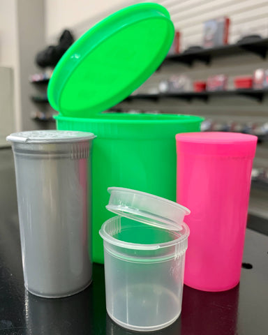 Green, silver, clear, and pink Loud Lock pop top vials are grouped together, some lids are open and some are shut.