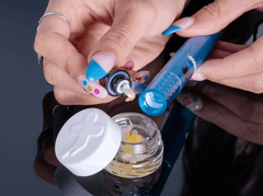 Woman uses the dab tool built into the mouthpiece of an Ooze Beacon wax concentrate vaporizer device to load the ceramic C-Core chamber with wax.