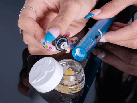 A girl with long nails is loading a dab into a blue Ooze Beacon extract pen