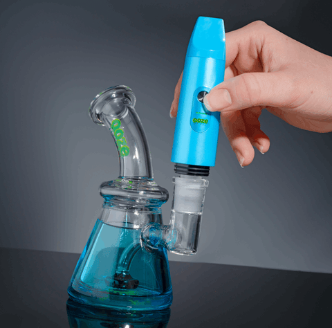 A blue Ooze Booster is being inserted into a blue Ooze Glyco freeze bong to create a torchless dab rig.