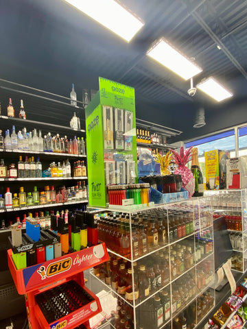 A wide angle shot of a gas station checkout counter featuring a case of liquor shooters, lighter displays, and a 48ct Ooze Twist Slim Pen 2.0 display