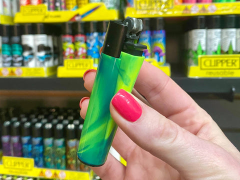 A girl is holding a green tie dye Clipper flint wheel lighter