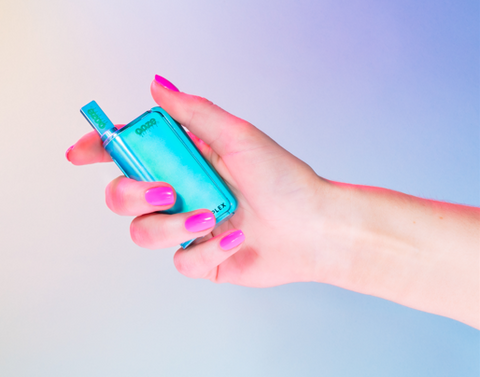 A white girl's hand with pink nails is holding an arctic blue Ooze Duplex Pro vaporizer