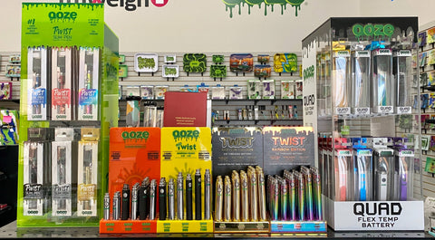 Ooze 510 thread vape pen battery displays are lined up together on a shelf in a convenience store