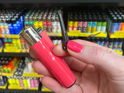 A girl holds a pink Clipper lighter with the poker tool removed and held to the side