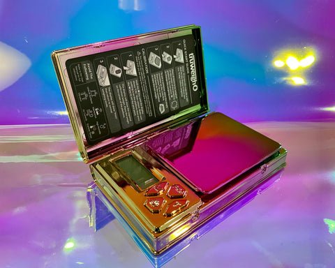 The rainbow Truweigh Shine scale is sitting on a holographic table with the hinged cover open