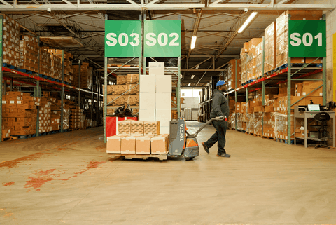 A worker pulls a cart full of boxes through the Cannatron warehouse