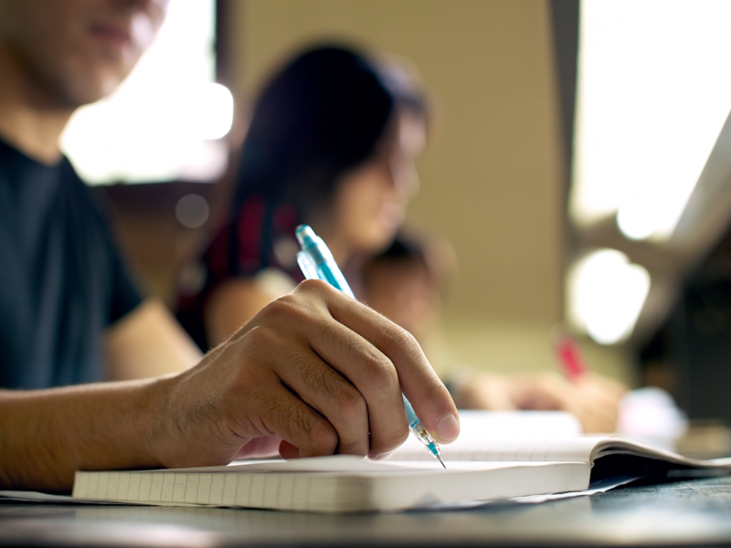 Close up of male student writing in notebook