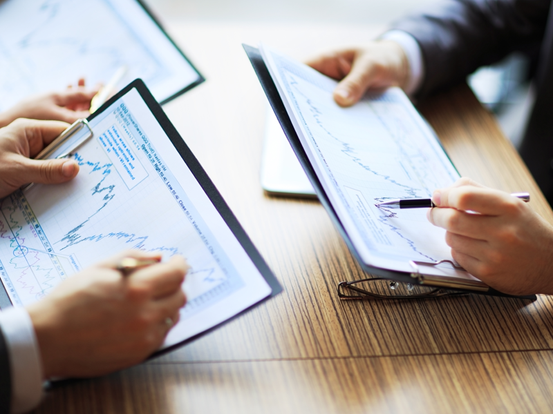 Cropped view of accountants reviewing printed financial documents