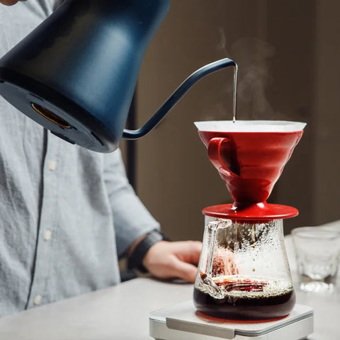 A person pouring coffee grounds into a coffee maker for brewing filter coffee.