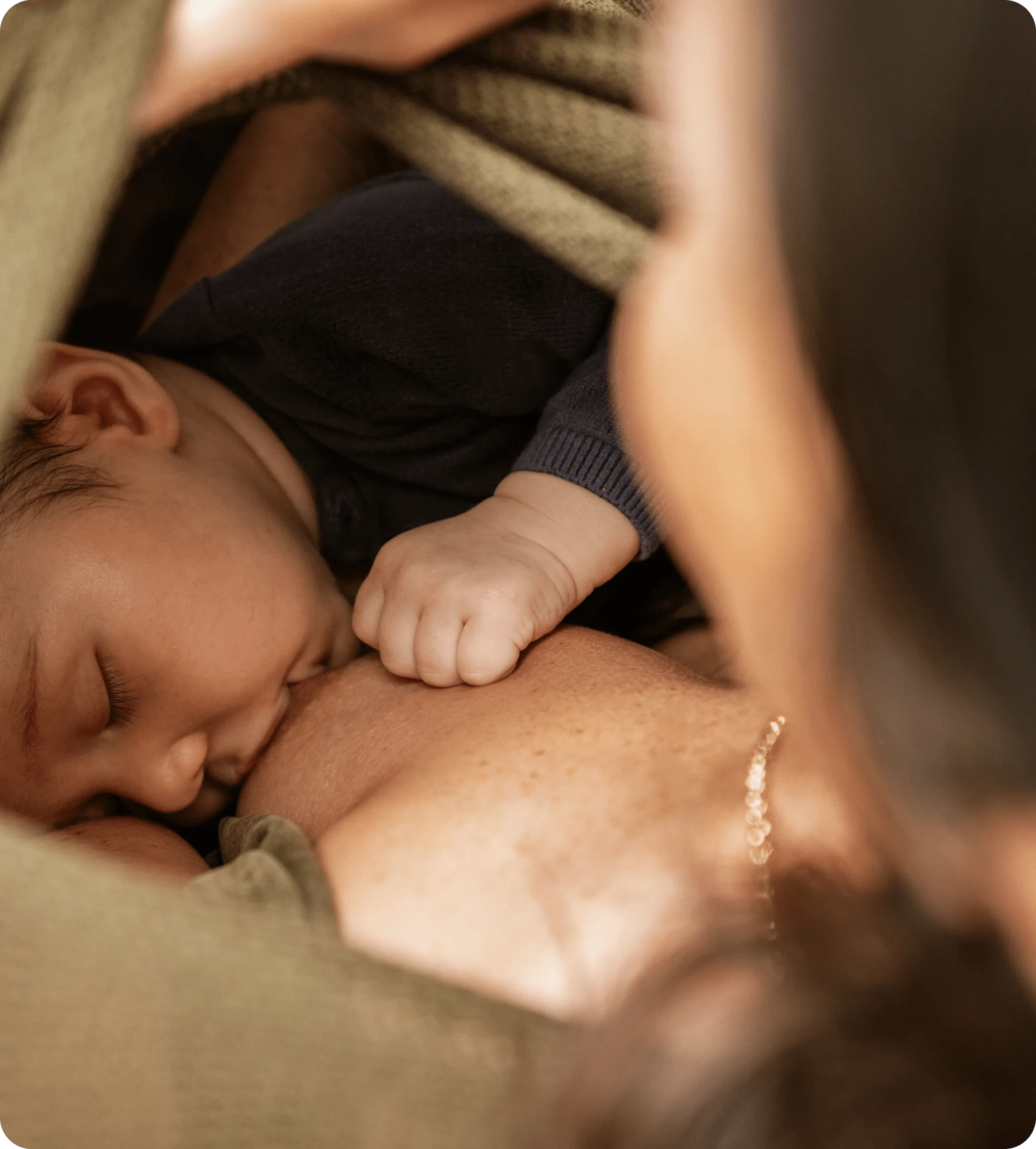 A baby breastfeeding while being cradled by a person.