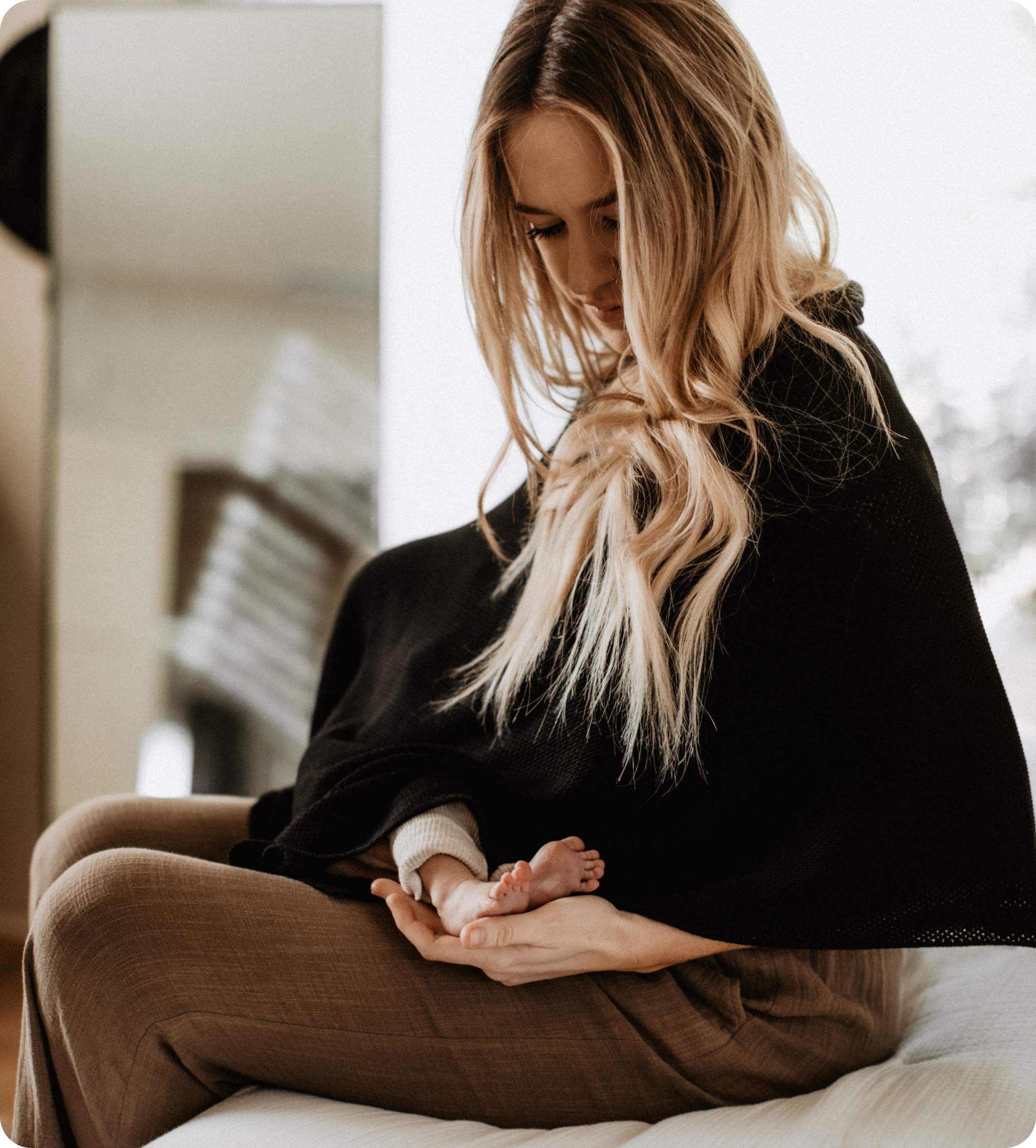 Woman gazing lovingly at baby feet in her lap.