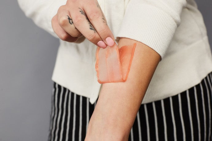 Woman pealing off the wax from her arm