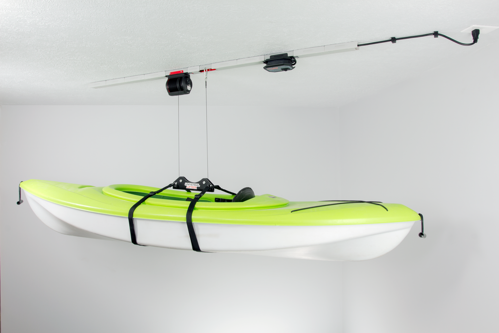 One green kayaks that are hanging from the ceiling of a storage unit. 