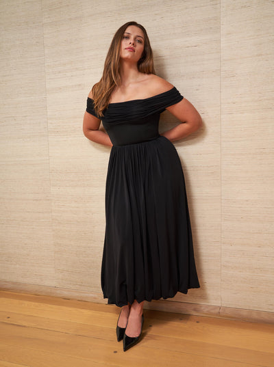 Channel your inner Grace Kelly and slip into this sleek, off-the-shoulder black dress with stretch bodice for the ultimate perfect fit.