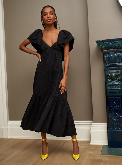 Make an entrance in this bewitching, black ruffle sleeve dress with open neckline. Equal parts romantic yet serious, the open back features a spaghetti strap adjustable tie for support as well as a smocked back for additional ease. Add some shirred tiers to this linen blend beauty and you have the perfect recipe for your dream dress this season.
