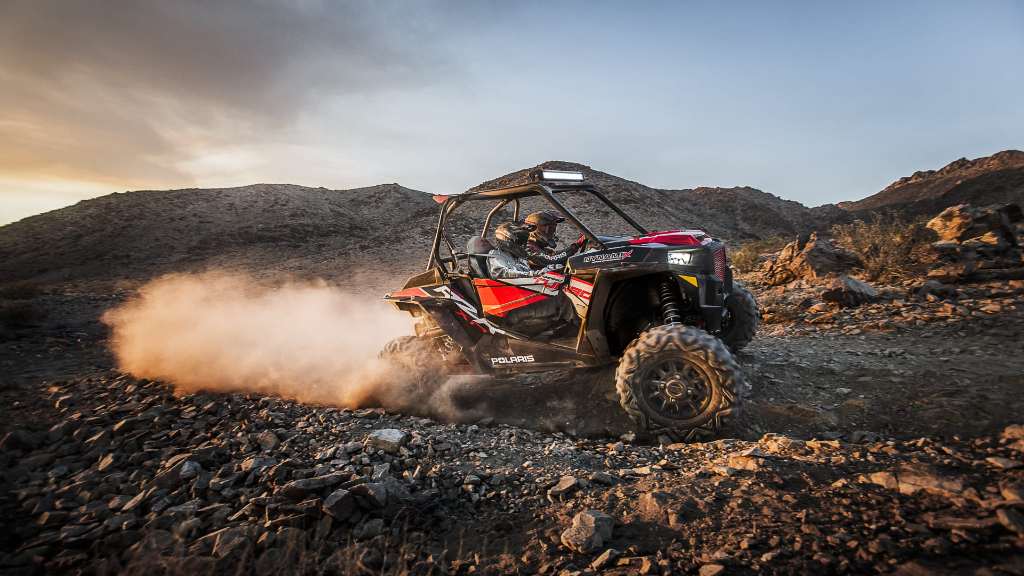 A Polaris RZR running fast on a rocky trail