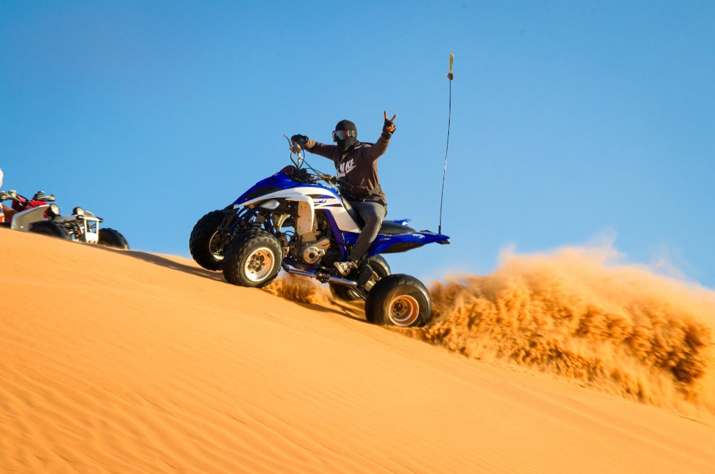 A man wearing goggles riding ATV in the desert