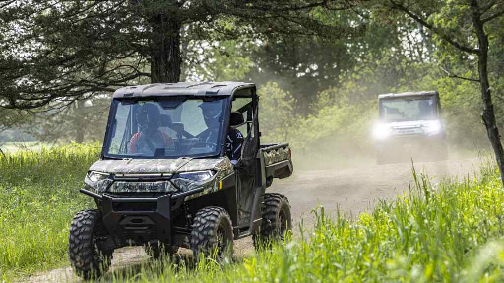 Electric UTVs running on a dusty trail