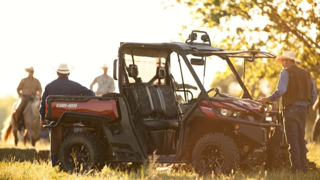 Men are gathering around a parked Can-Am Defender.