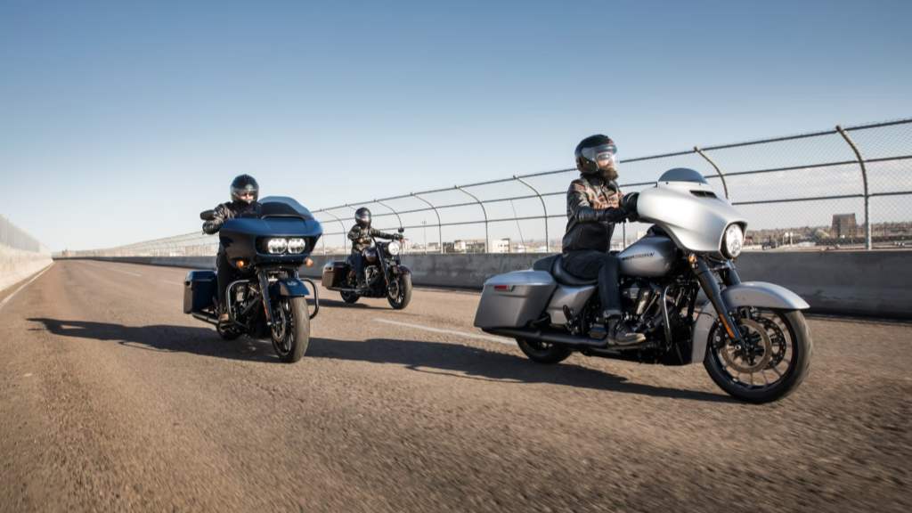 Three men are riding touring motorcycles on the open road