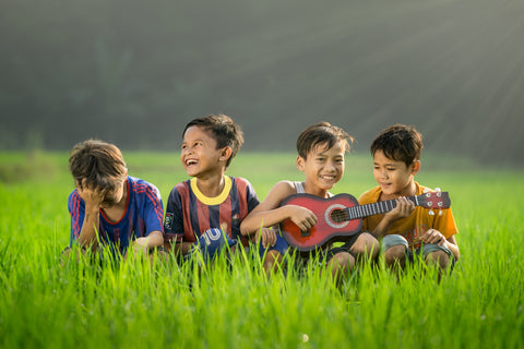 four boys, one playing a ukulele