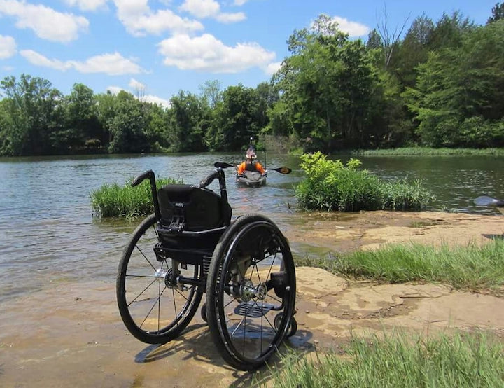 wheelchair sitting on the shore with its owner in a kayak on the water