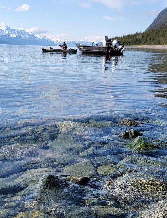 Josiah kayaks on a calm Alaskan sea away from an anchored boat