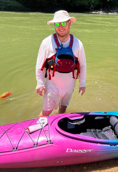 Jarrid Snyder stands next to his kayak on the riverbank