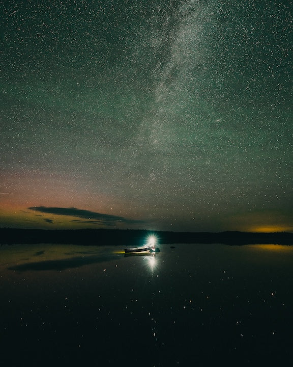 canoe sits on shore at night under the Milky Way
