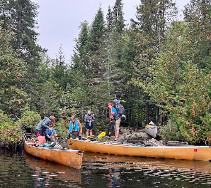 canoe trippers load up canoes at a Boundary Waters portage