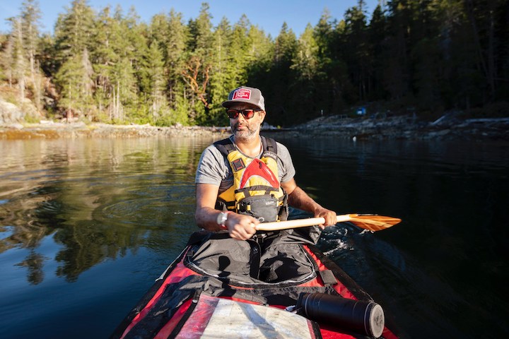 man using a bent shaft canoe paddle in the stern