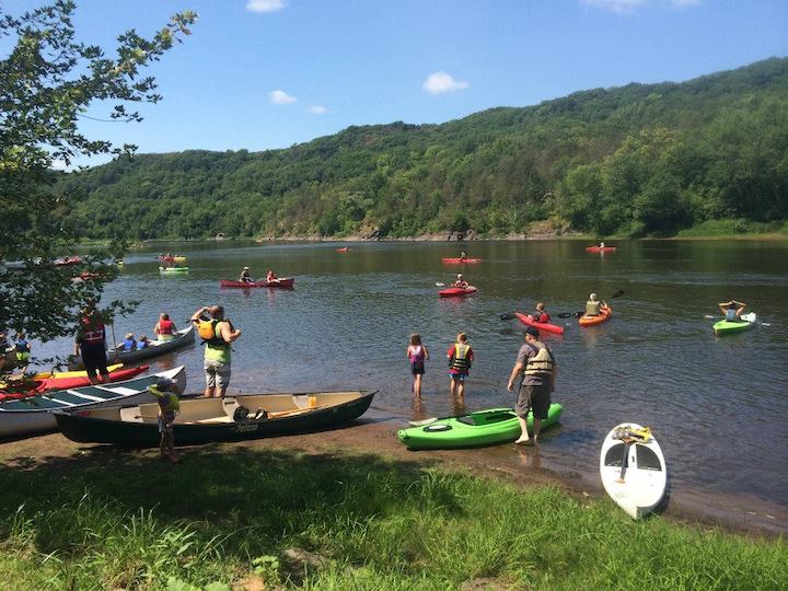 a group of people getting on a river in canoes, kayaks and SUPs