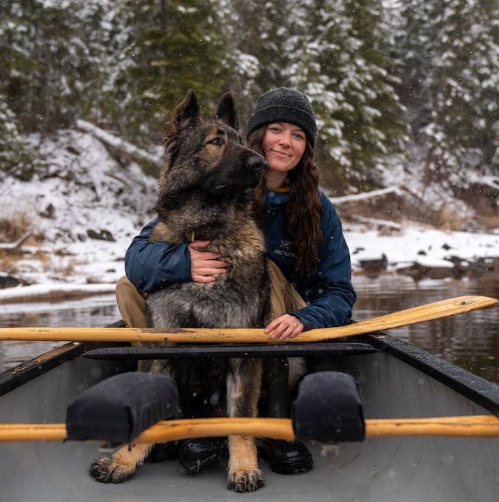 Ashley Bredemus with her dog Arlo in a canoe in winter, with her Bending Branches paddle