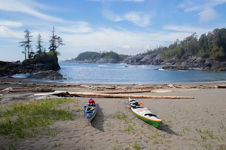 two sea kayaks sit on the shore of the Alaskan coastline