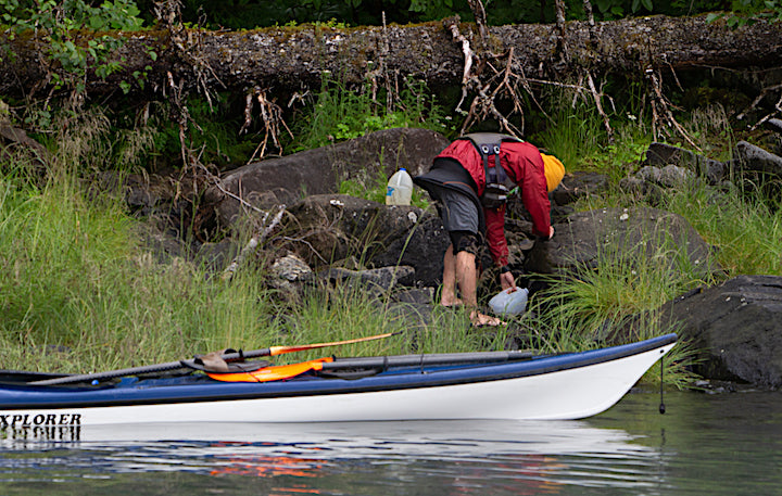 collecting water from a creek, near a kayak onshore