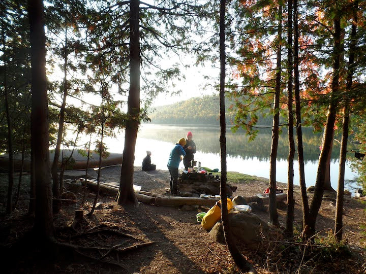 campers in the early morning at a canoe campsite next to a calm lake