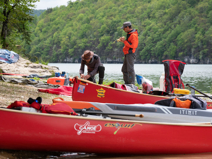 two men with their canoes and gear on-shore