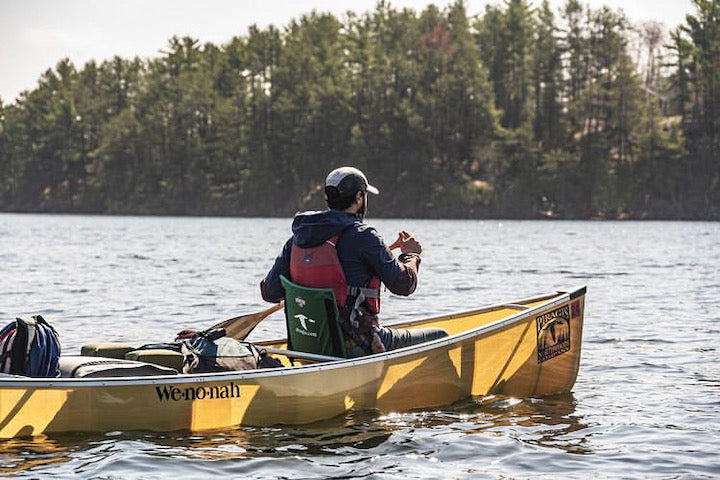 man paddling in canoe bow sitting in a seat with a backrest