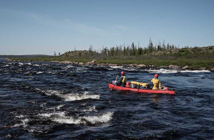 two canoeists take their canoe down a whitewater section of the Dubawnt River
