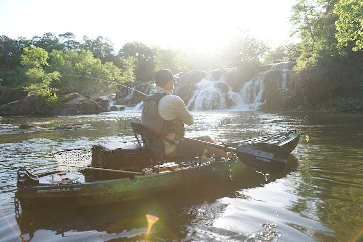 kayak angler fishes in front of a waterfall